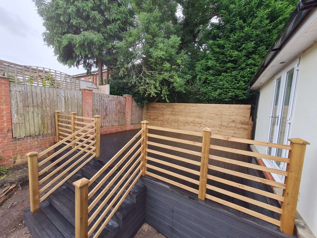 Black garden decking with timber handrails and privacy screen in Staffordshire