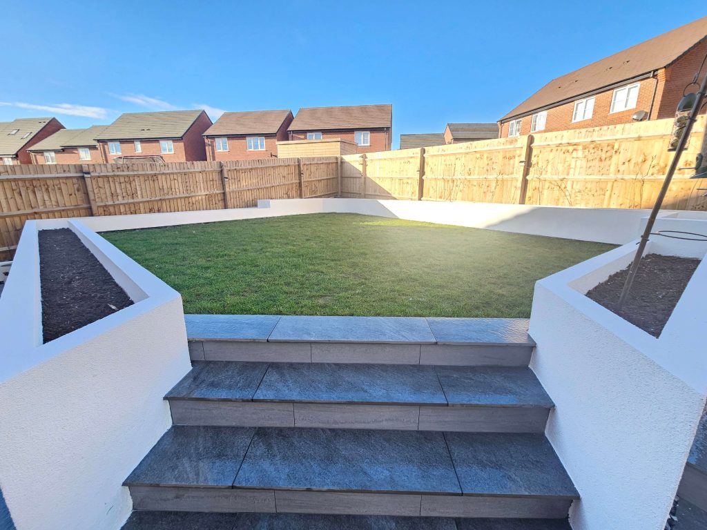 Raised landscaped garden with lawn, tiled steps and timber fencing in Staffordshire
