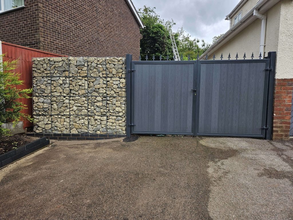 Grey driveway gates with gabion stone wall in Staffordshire