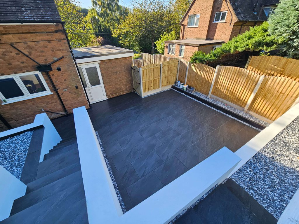 Modern patio garden with dark tiles, rendered walls and timber fencing in Staffordshire