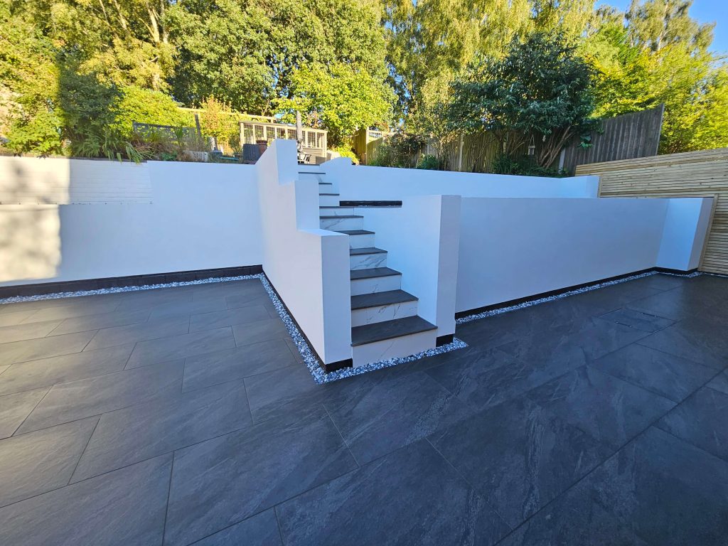Modern landscaped garden with dark patio tiles and rendered walls in Staffordshire